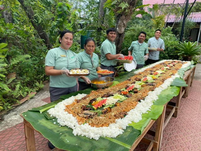 Our team hard at work setting up this table for a boodle fight! 💚 

A Filipino communal dining experience where food is piled high on a long table covered with banana leaves, and everyone is encouraged to eat with their hands, fostering a sense of camaraderie and fun.